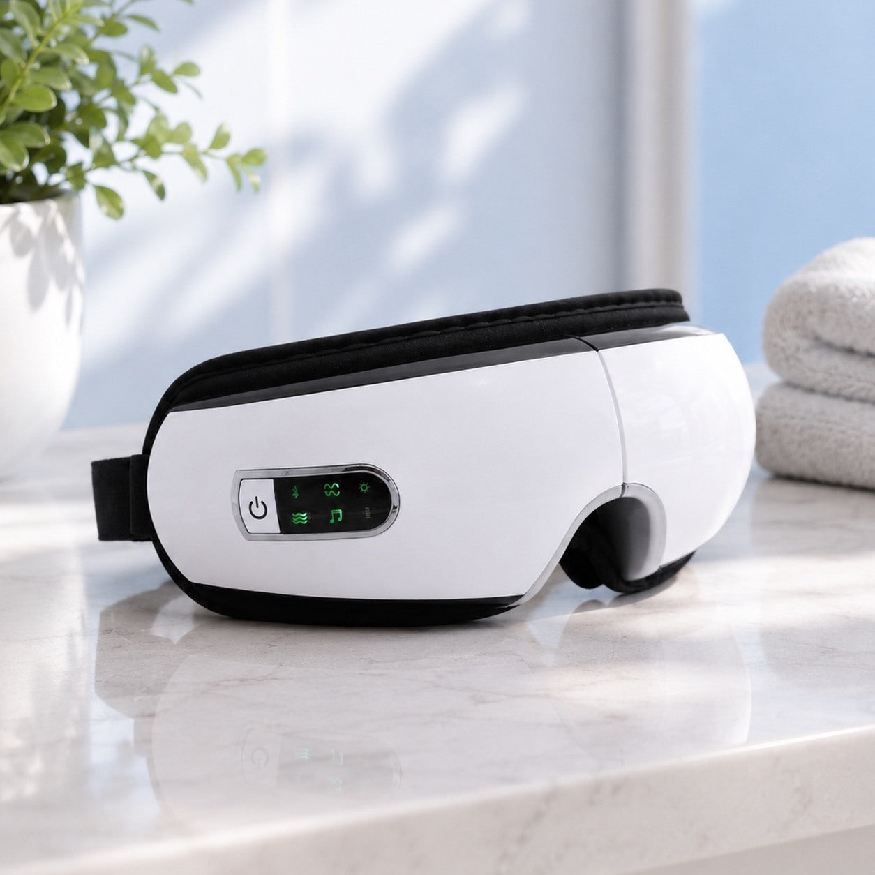 The massager resting on a marble surface next to a plant and folded towels